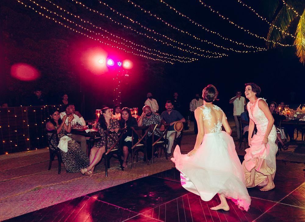 Wedding celebration on an outdoor dance floor with string lights and pink ambient lighting.