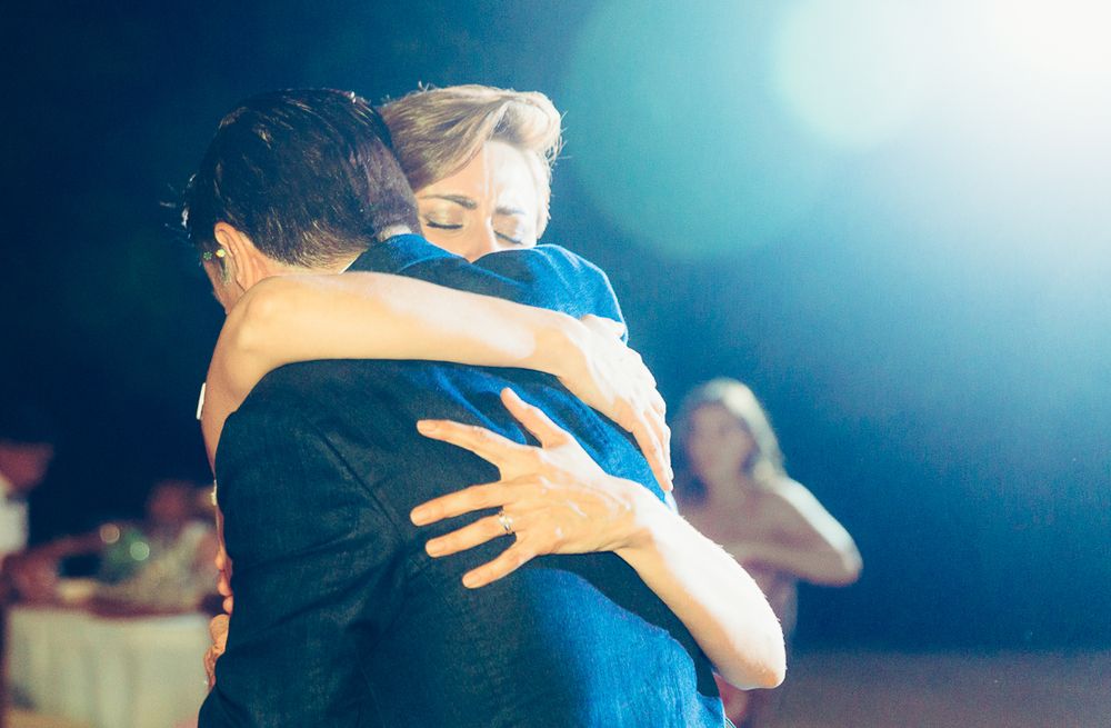 Emotional dance moment under blue lighting at evening wedding reception.
