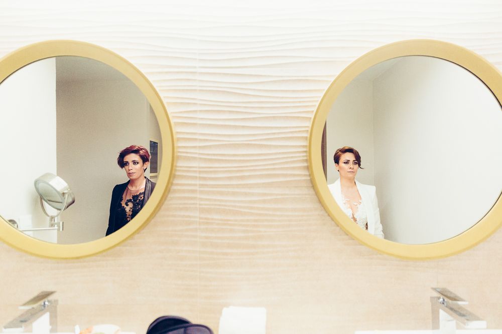 Creative wedding day preparation photo captured through two circular bathroom mirrors.