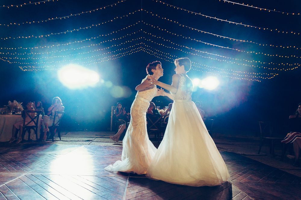 A romantic first dance moment captured on a dance floor beneath blue lighting and fairy lights.