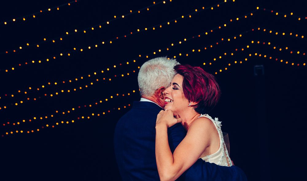 Romantic dance under twinkling lights at outdoor evening reception.