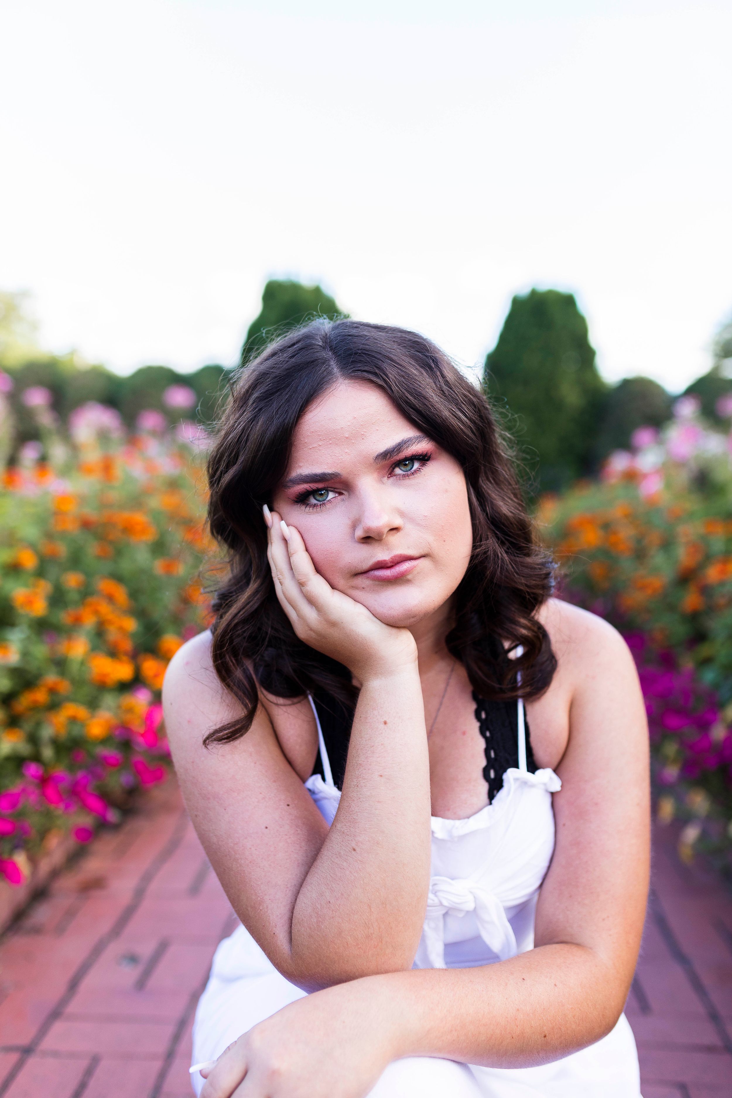 Portrait in garden with colorful flowers and warm evening light.