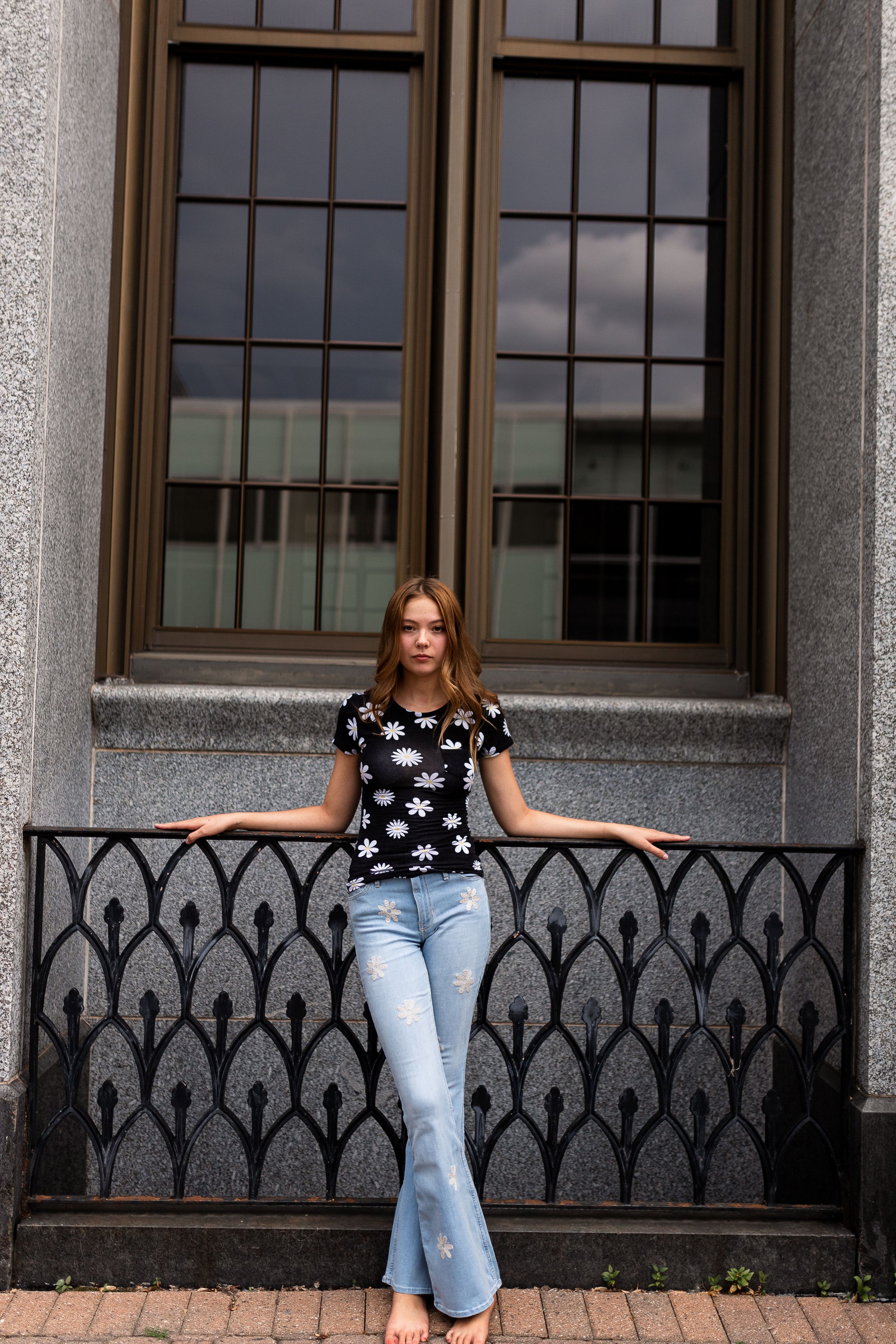 Casual portrait against architectural background with ornate iron railing.