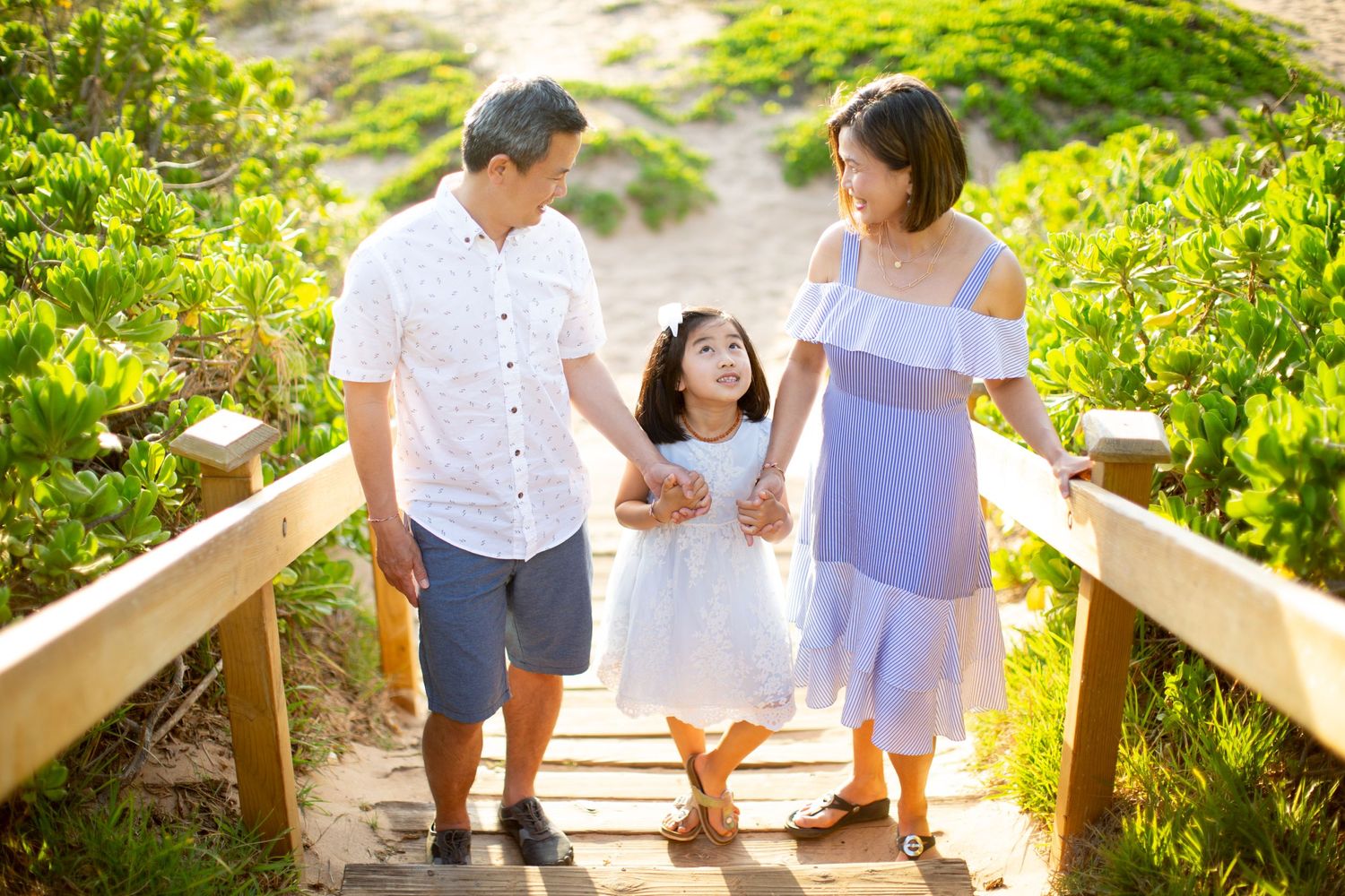 A group walks together down wooden steps surrounded by lush tropical vegetation.
