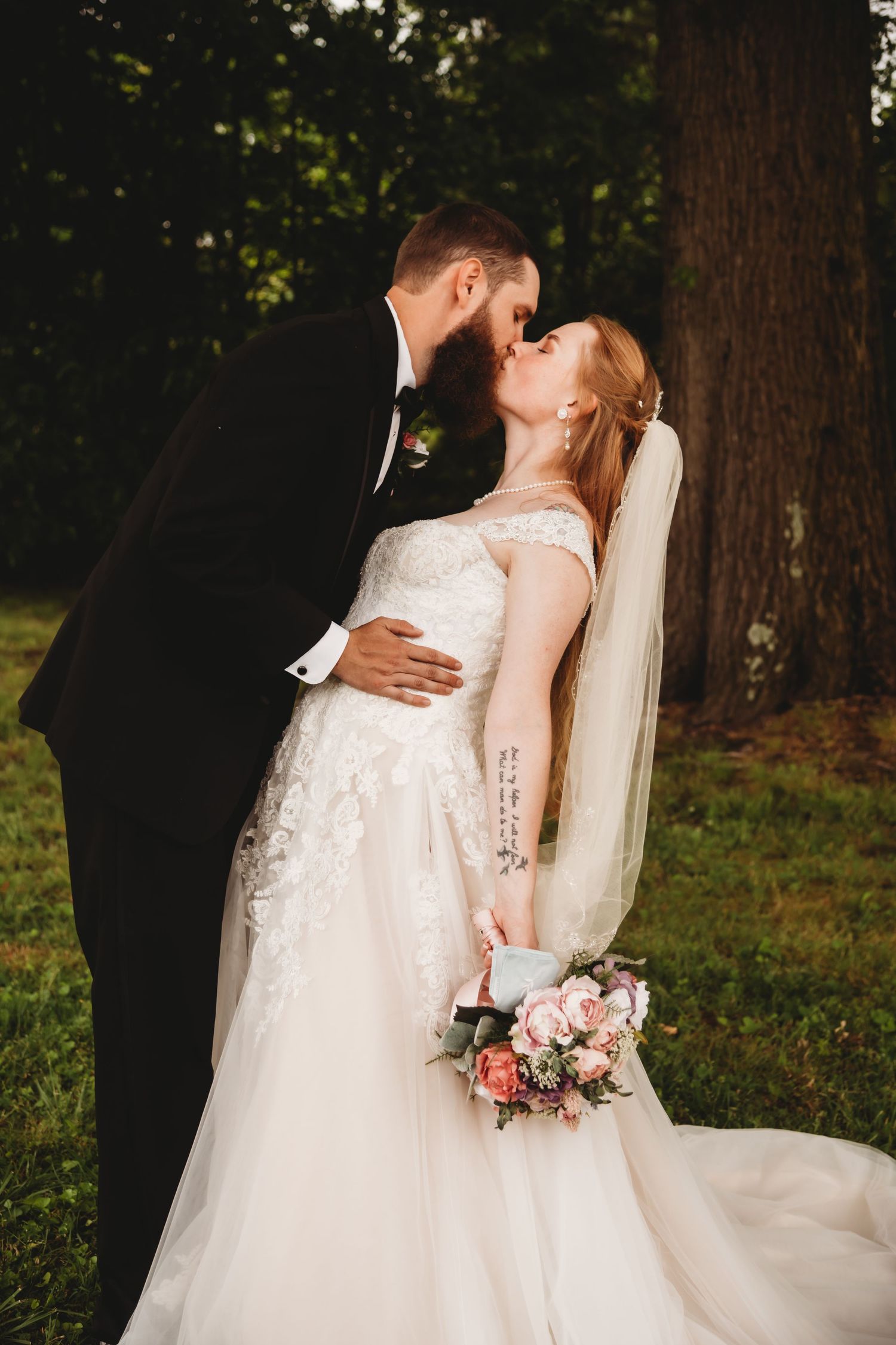 A romantic wedding moment captured with the couple sharing a kiss in a garden setting.