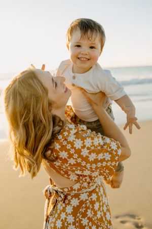 A joyful beach scene with floral dress against golden sunset light.