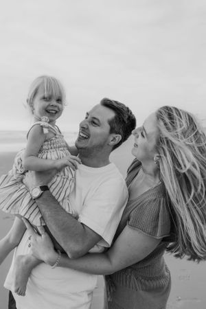 Black and white photos showing genuine laughter and joy during a family beach session.