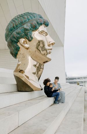 People sitting on concrete steps beside a large turquoise sculptured head.