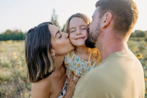 A tender family moment captured in a golden field during sunset.
