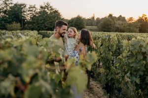 A joyful family moment captured between rows of grapevines at sunset.