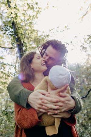 A tender family moment captured in warm autumn light among trees.