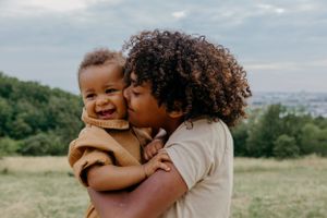A joyful family moment captured against a cloudy sky during an outdoor photoshoot.