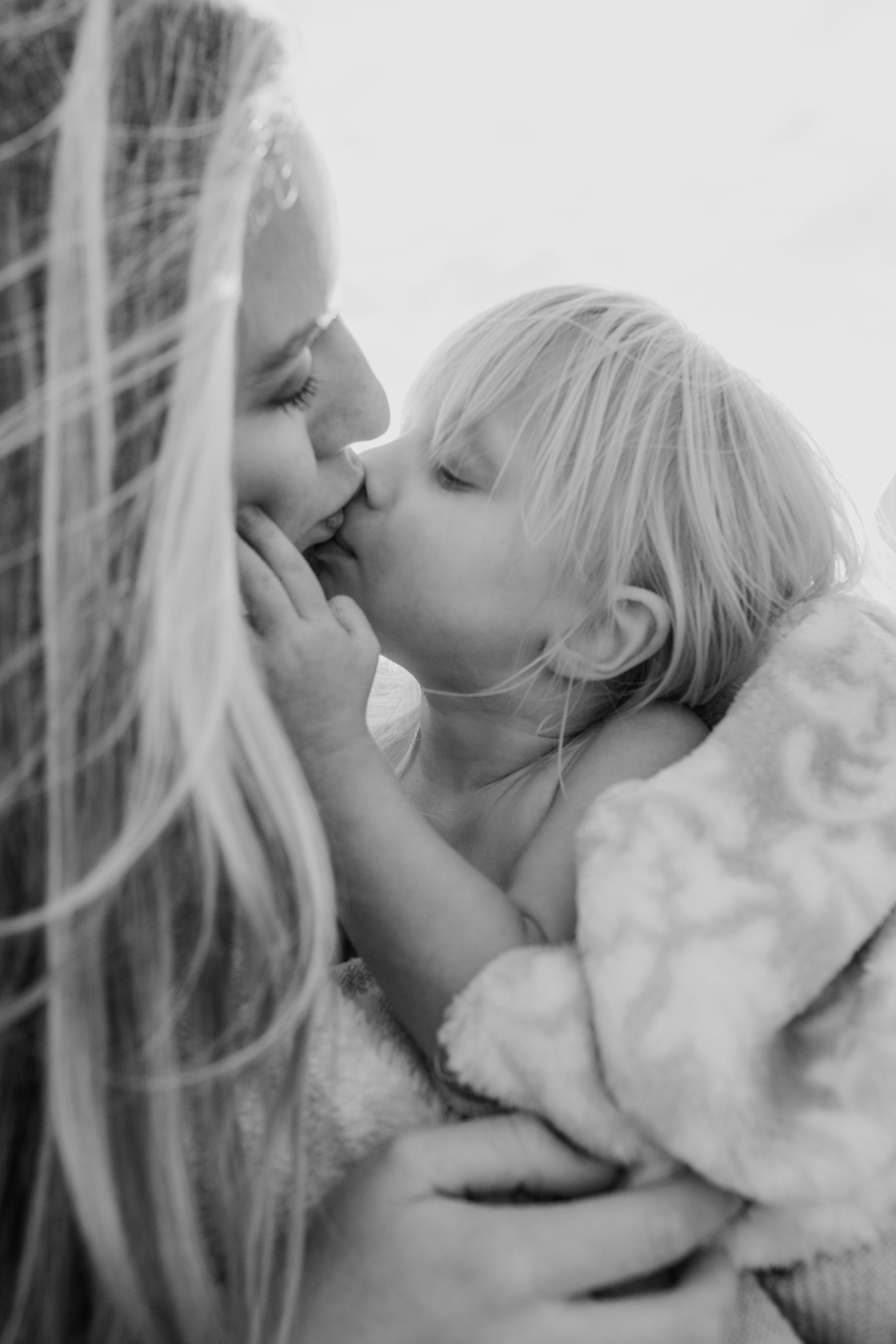 Black and white intimate portrait showing tender affection and gentle touch between parent and child.
