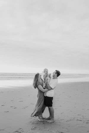 Black and white beach photos capturing intimate family moments in the sand.