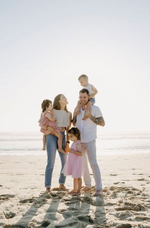 A family shares joyful moments together on a sunny beach at sunset.