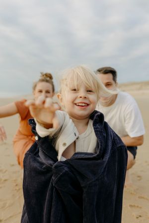 Candid expressions of joy captured during a beach photoshoot on a cloudy day.