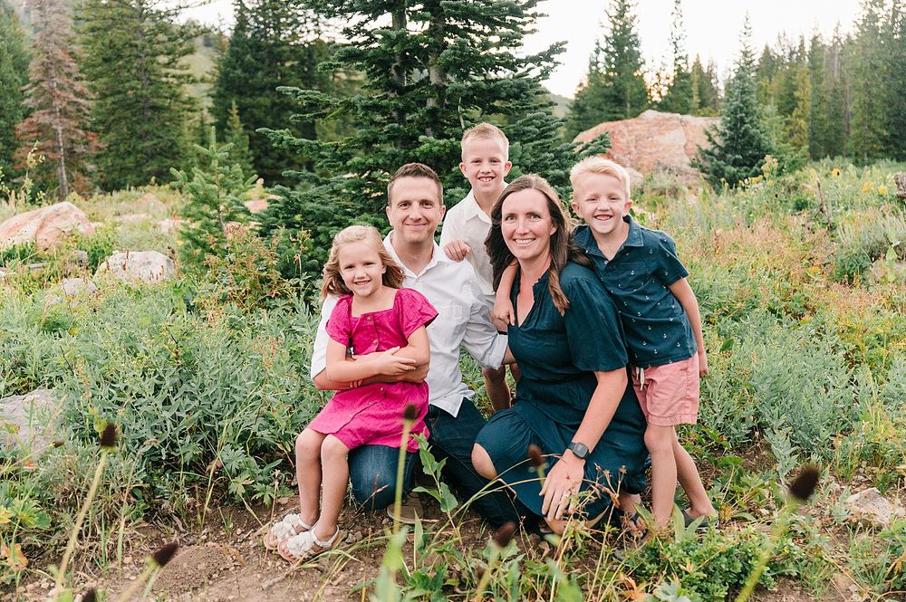 Family group portrait in an outdoor mountain setting with evergreen trees and natural rock formations.