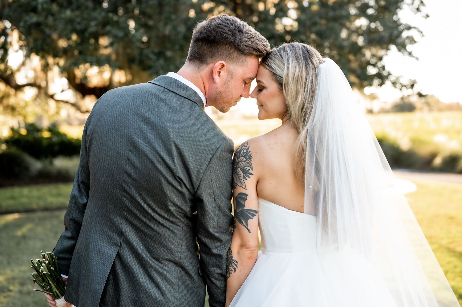 A romantic wedding portrait session captured in golden evening light under oak trees.