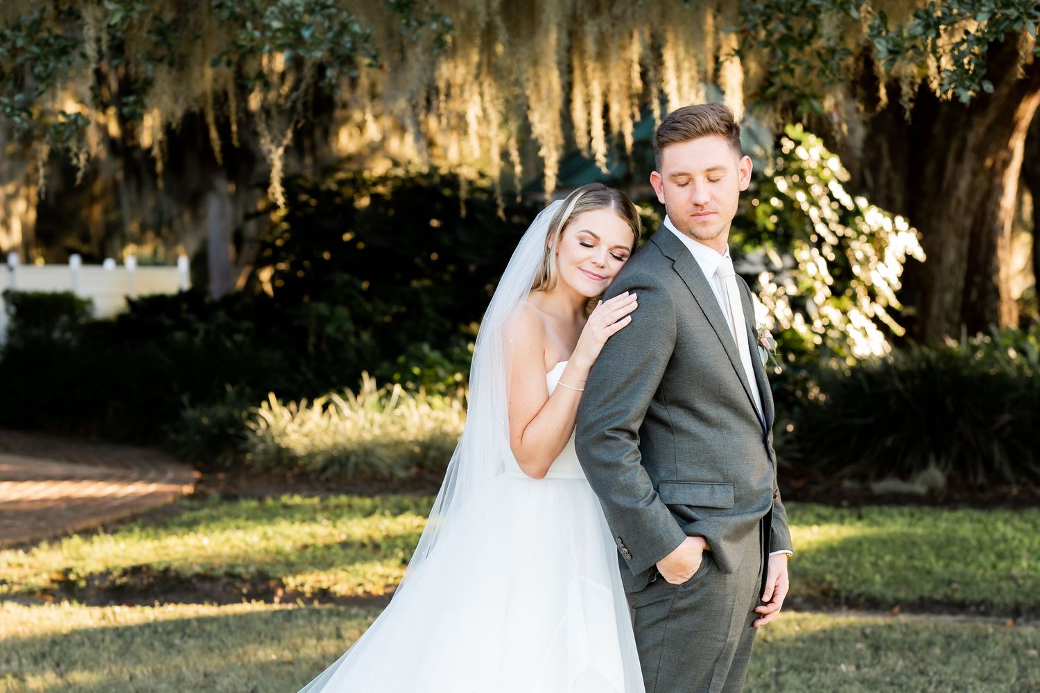 Wedding couple embraces during an outdoor photo session with Spanish moss in the background.