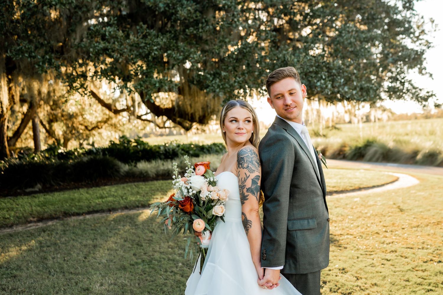 A couple poses in golden sunset light at their outdoor wedding ceremony.