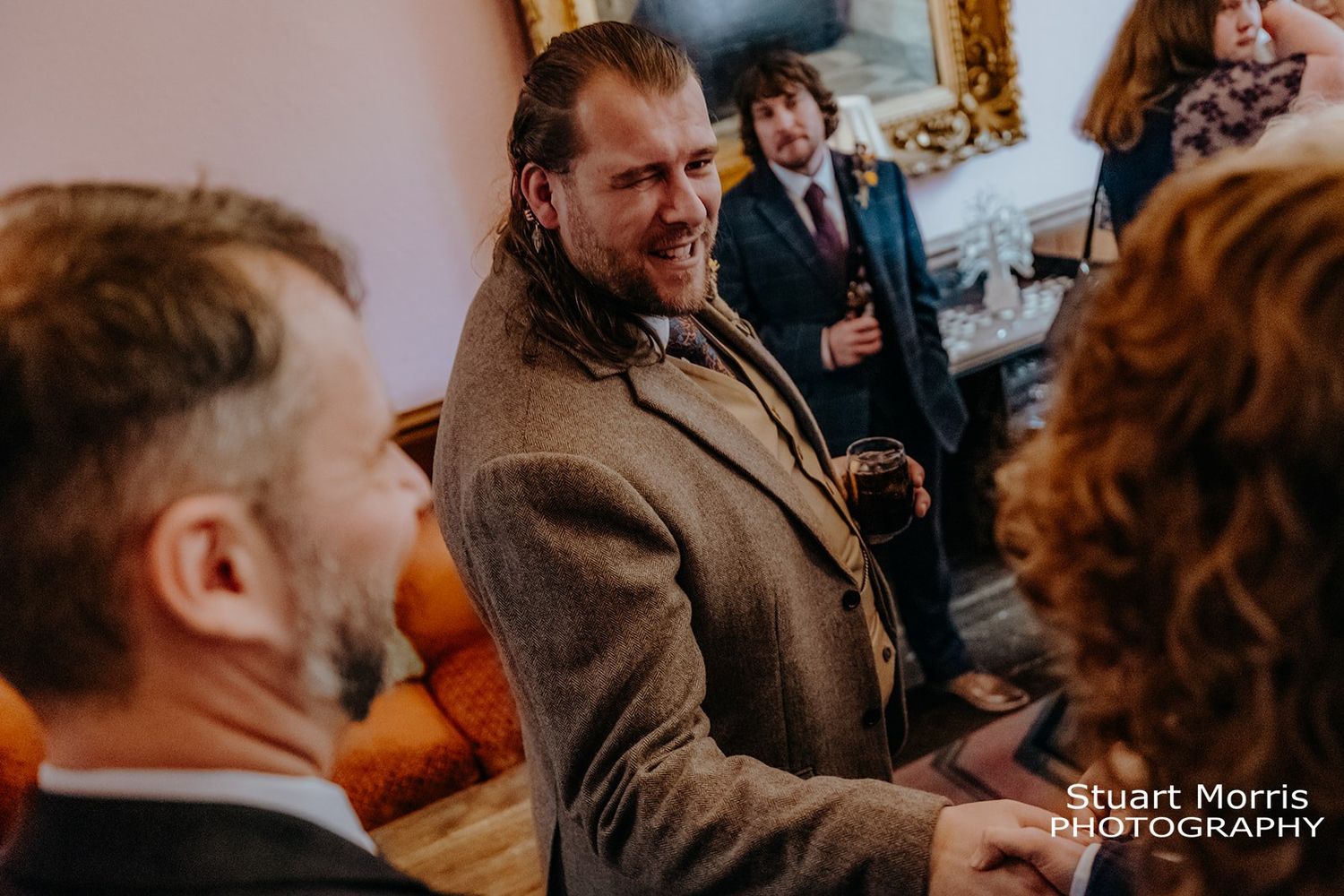 groom gets a handshake from a wedding guests mingling after the wedding ceremony. Ruthin castle wedding photography.