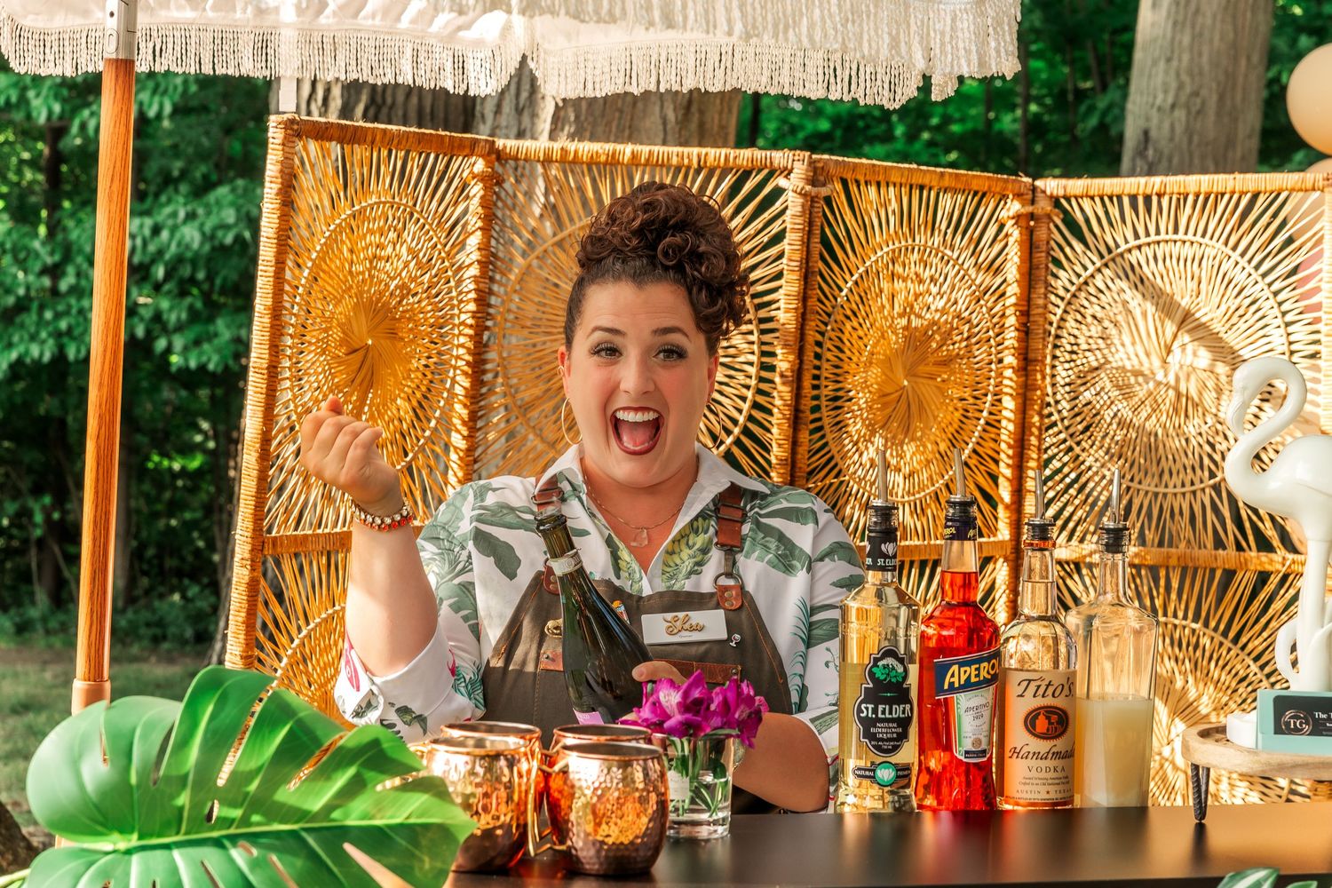 Tropical-themed bar setup with woven bamboo backdrop and cocktail ingredients.