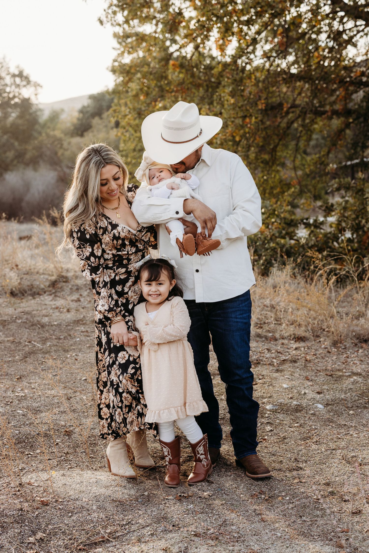 A family poses together on a rustic trail during golden hour.