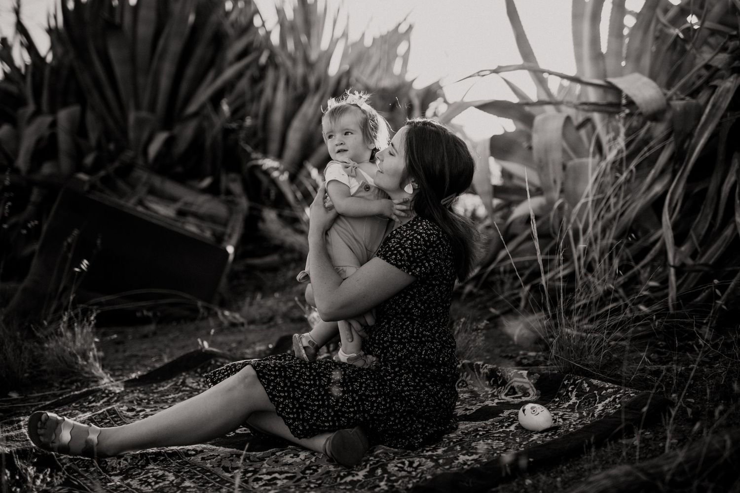 Moody black and white capture of family bonding on blanket outdoors.