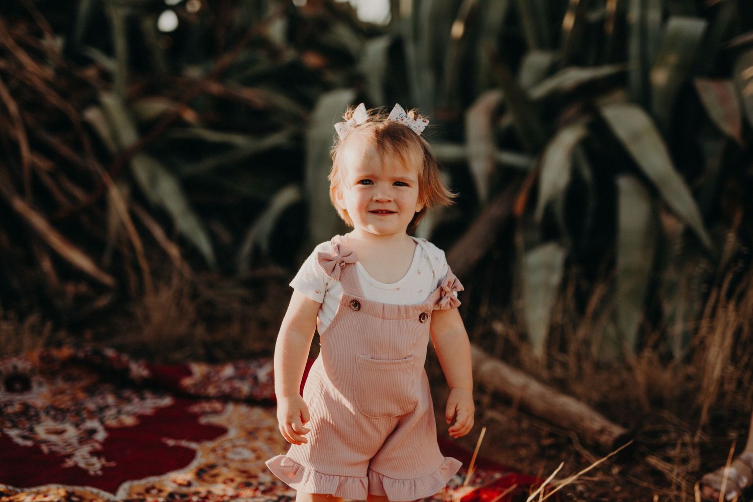 Child playing outdoors in a garden setting with natural lighting and foliage in the background.