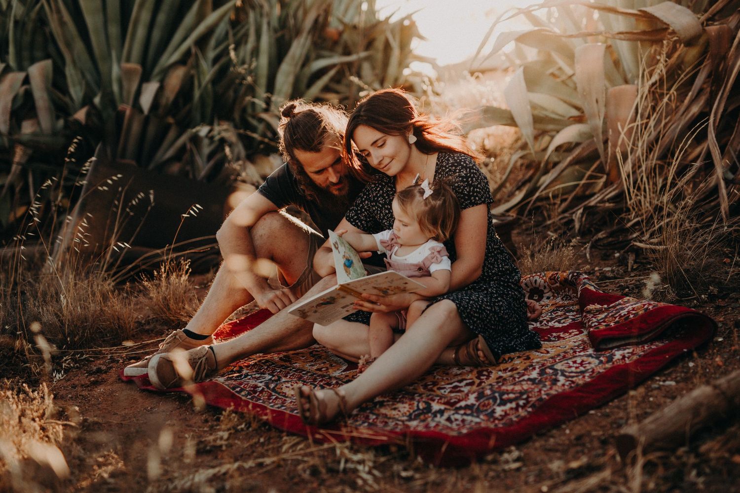 Lifestyle family photography session at sunset with tropical plants in background.