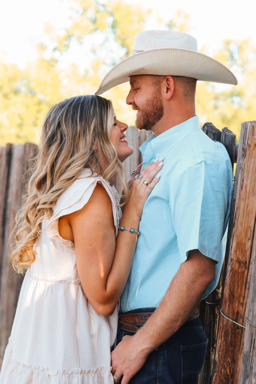 Romantic couple portraits against a wooden fence in casual summer outfits.