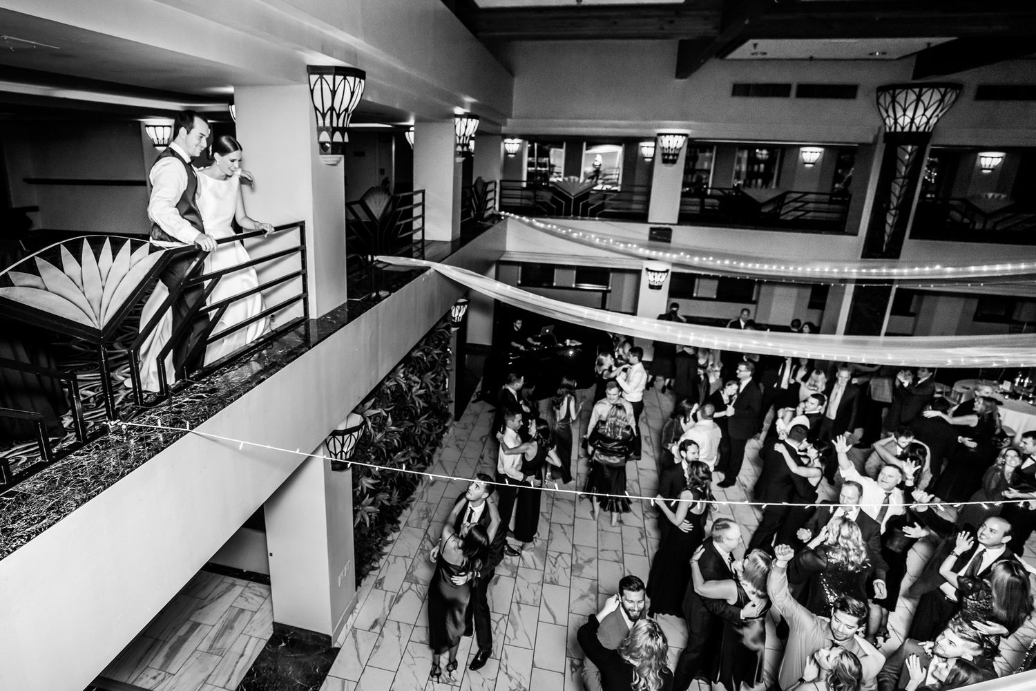 Bride and Groom observing their party from the balcony of their venue.