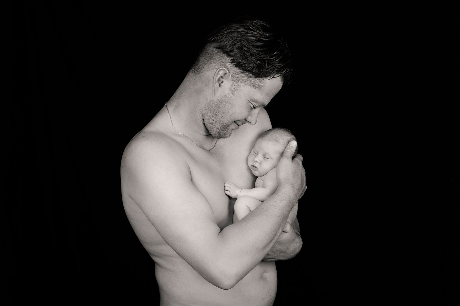father holding newborn baby boy in embrace