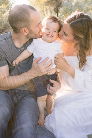 A joyful family moment captured outdoors with warm sunlight filtering through the background.