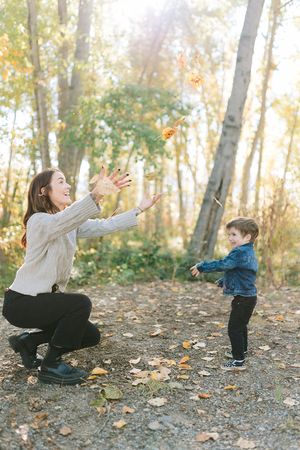 Mother and child playing together on autumn trail surrounded by golden trees.