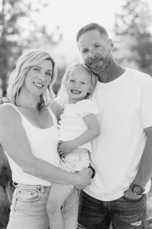 A casual outdoor family portrait with bright smiles and natural lighting.