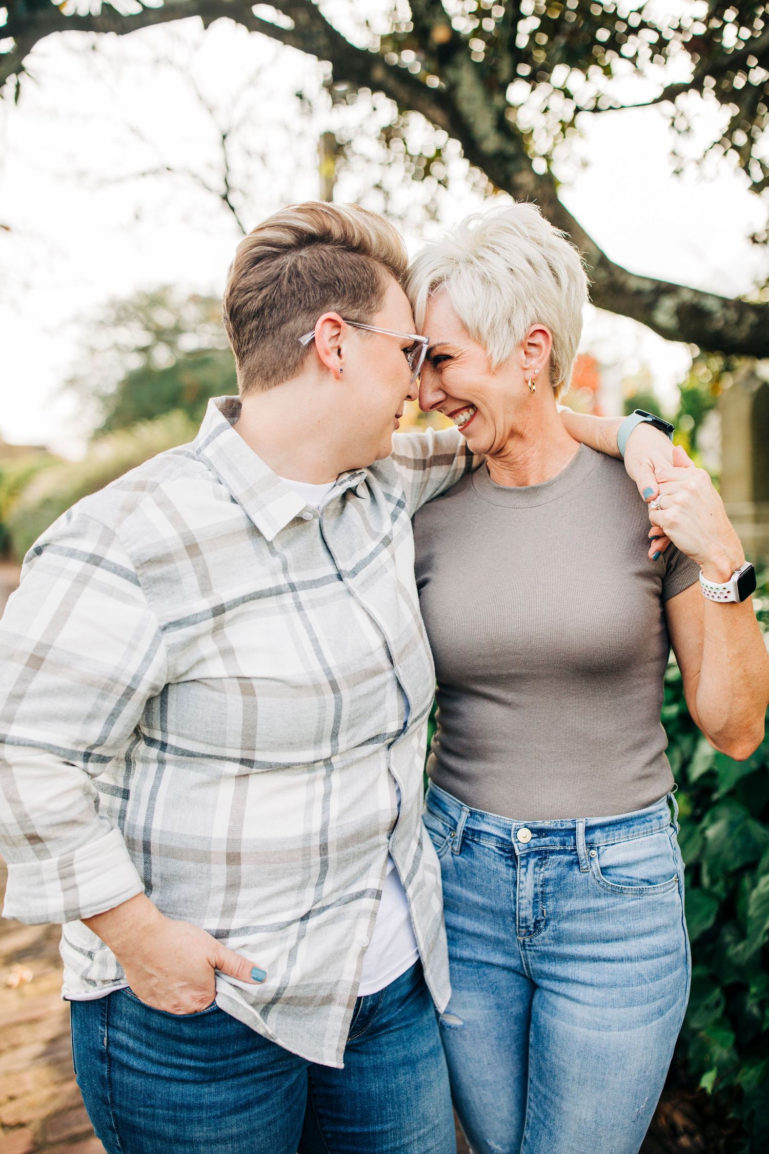 A couple shares an intimate moment outdoors, leaning in close together and smiling.