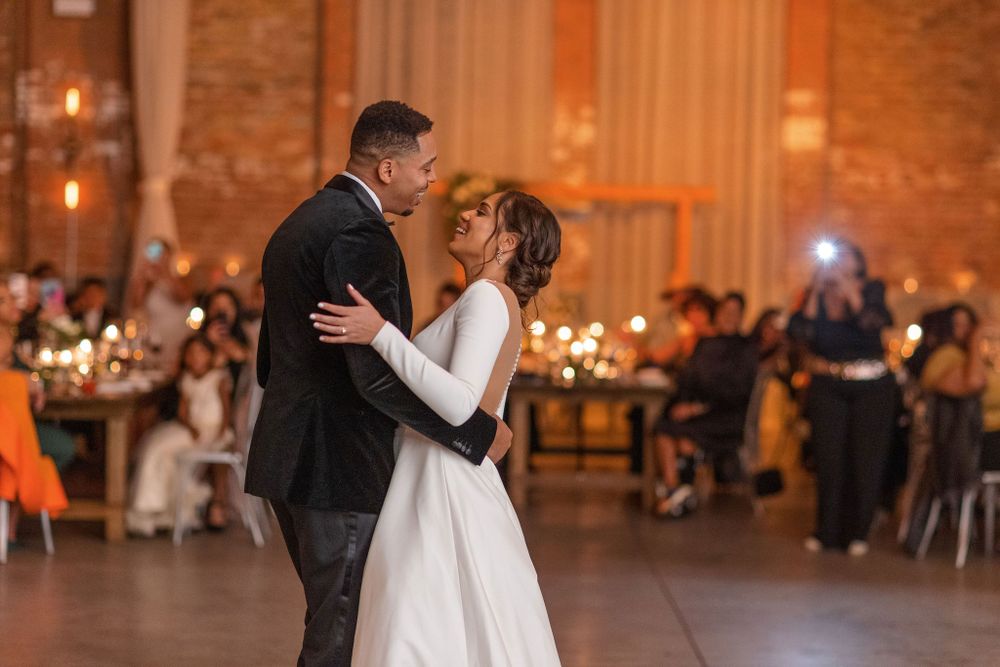 Wedding couple dancing together in an elegantly lit brick venue during reception.