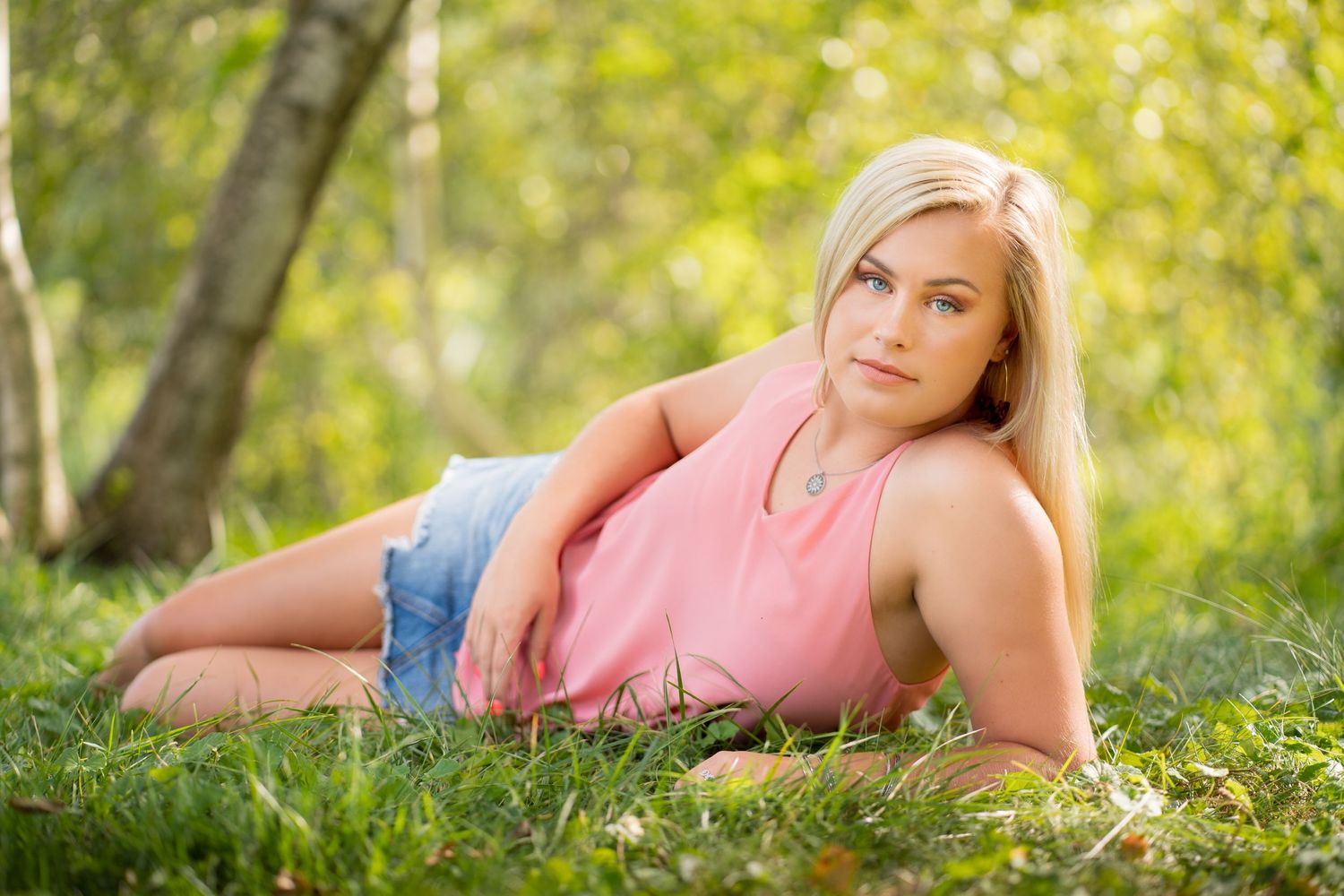 Summer portrait session with pink top in sunlit grass.