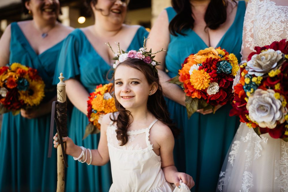 Colorful autumn wedding bouquets featuring sunflowers and orange blooms against blue dresses.