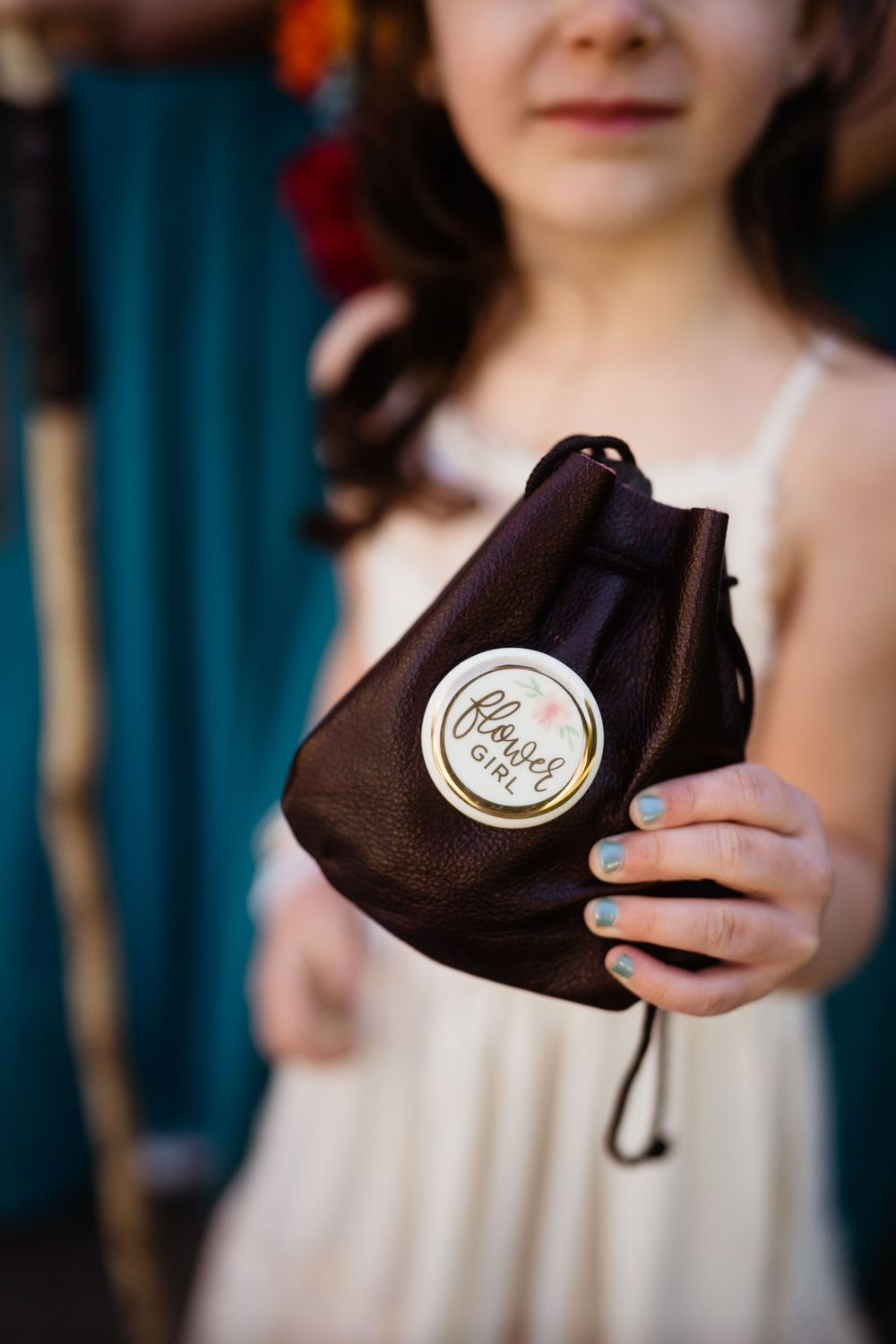 Close-up of hands holding a small brown velvet drawstring bag with a wedding logo.