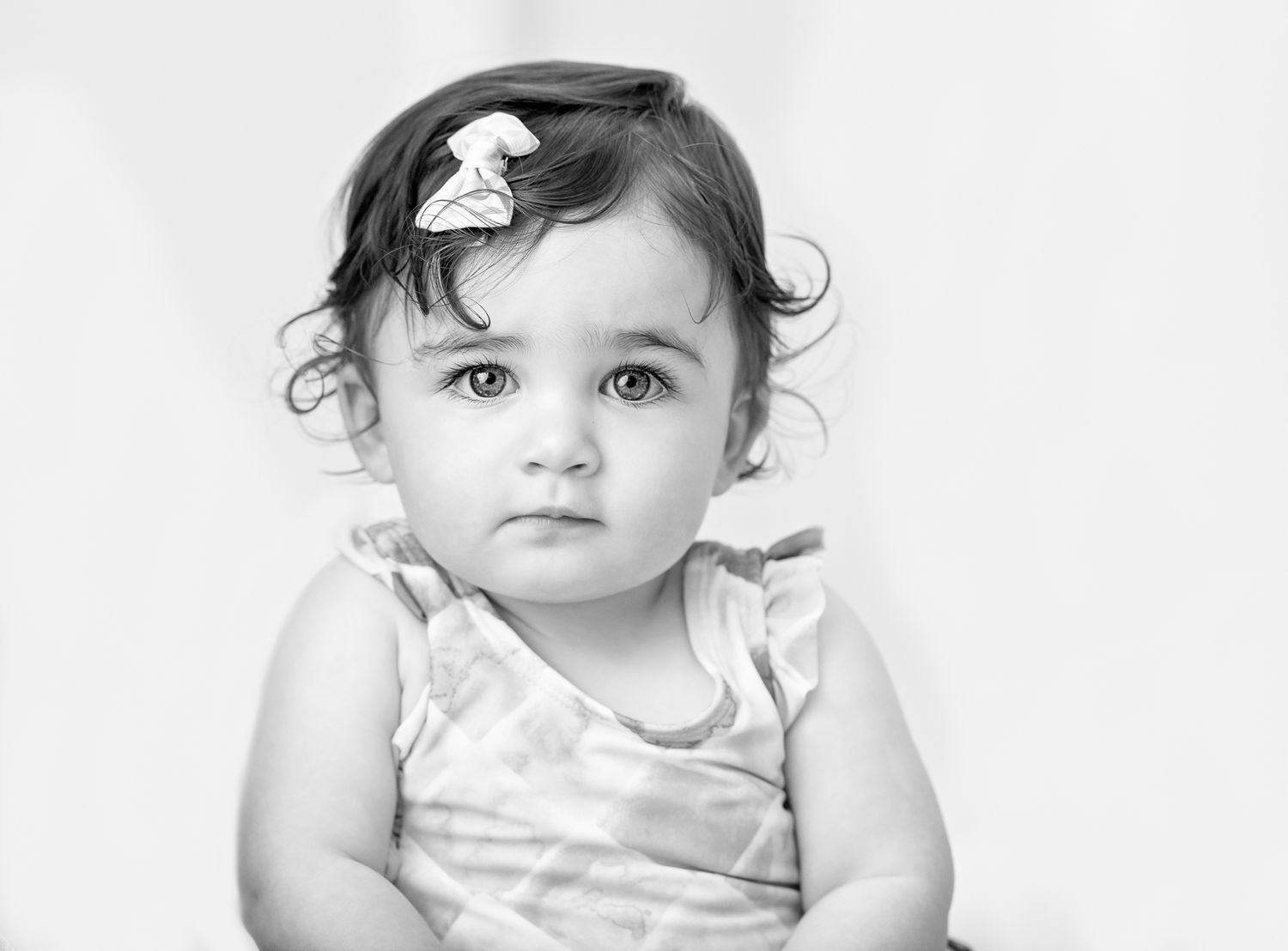 High key black and white portrait series in minimalist studio setting.