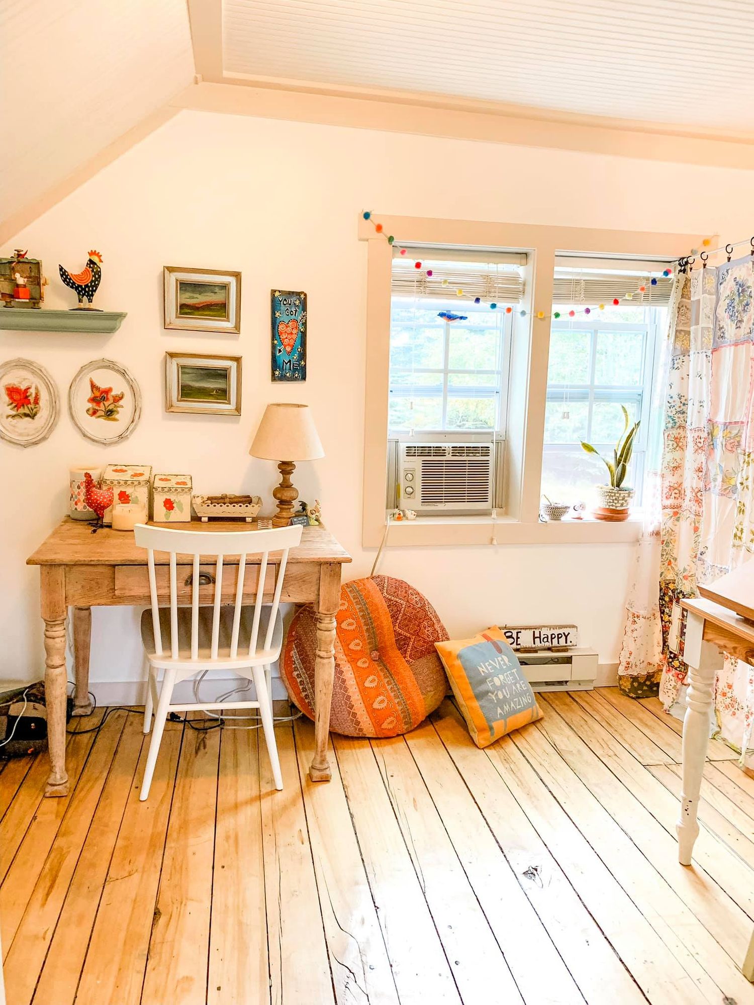 A panoramic view of a cozy cottage interior with light wooden floors, white walls, and orange accent decor.