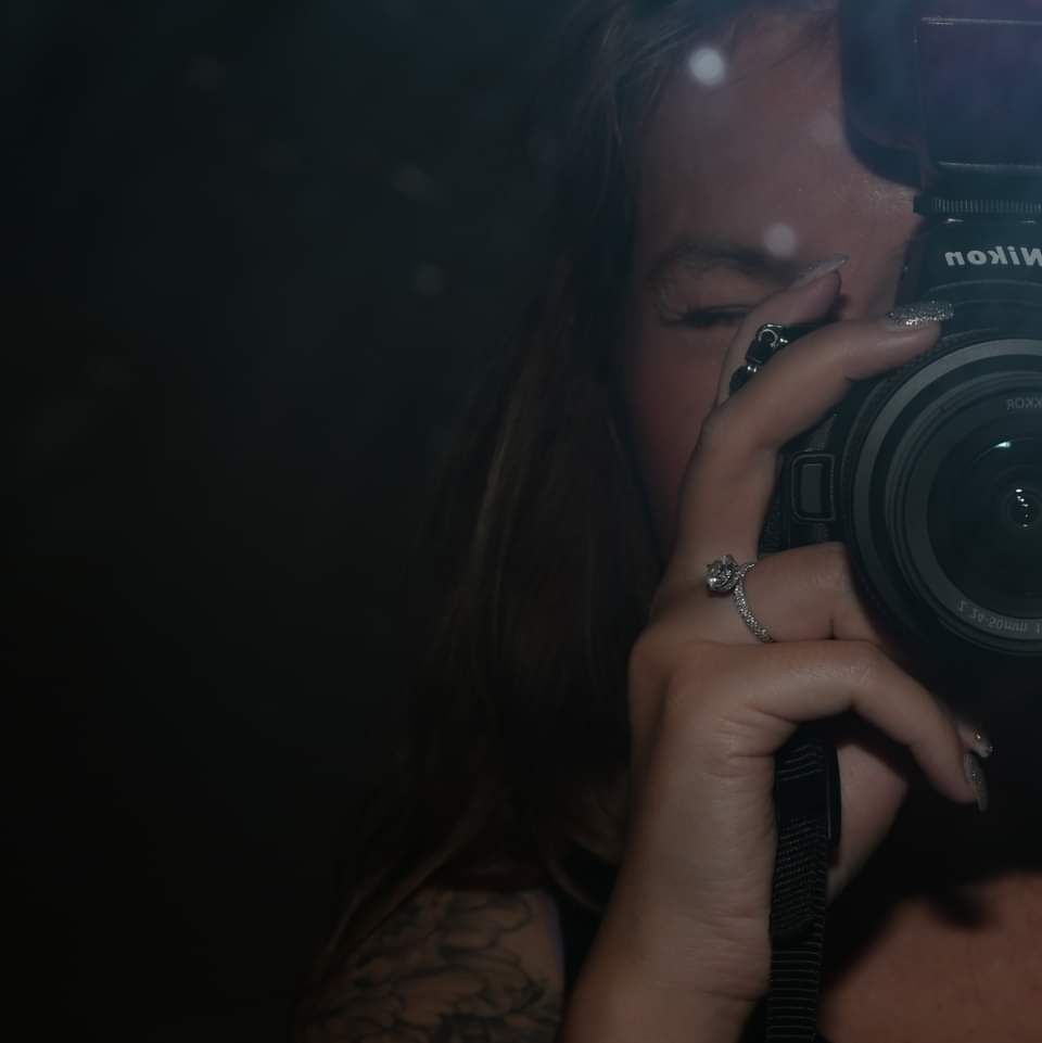 Artistic dark photograph of photographer taking picture with professional camera.