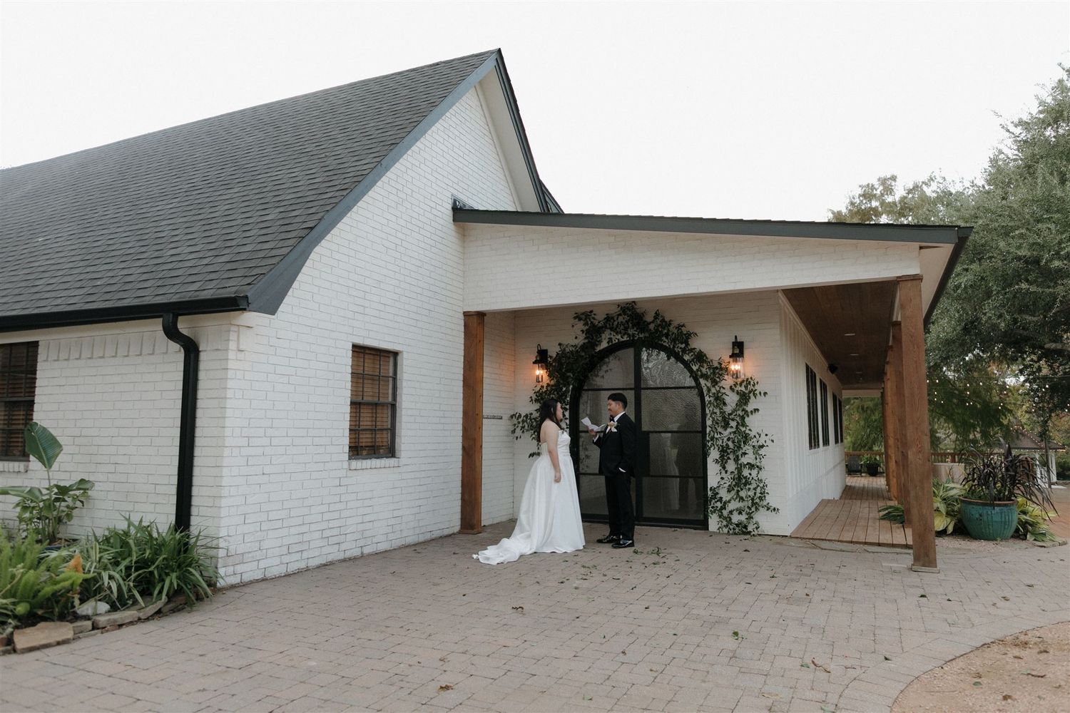 White modern chapel exterior with wooden beams and arched entrance for a wedding ceremony.