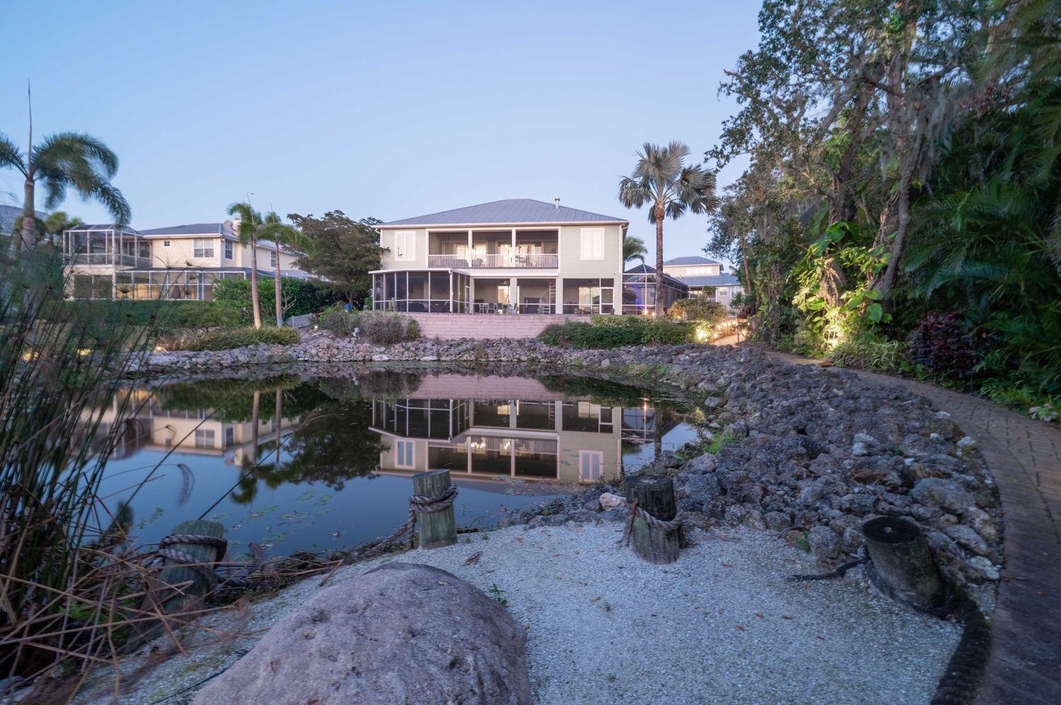 Luxury waterfront home with reflection in still pond at dusk.