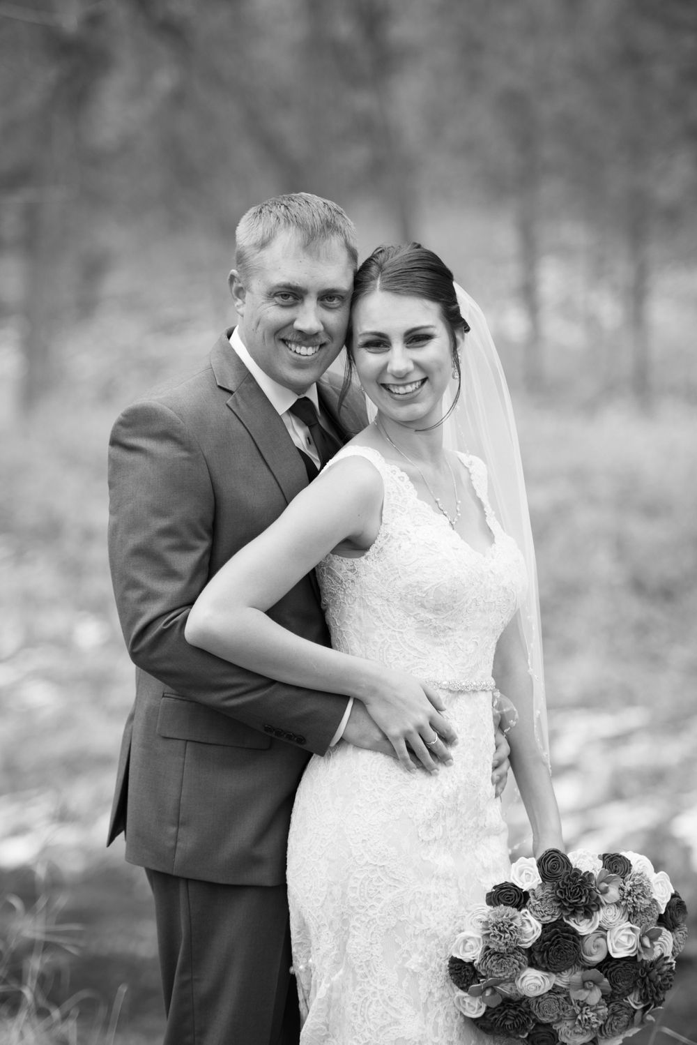 Black and white wedding portrait with couple sharing intimate moment and floral bouquet.