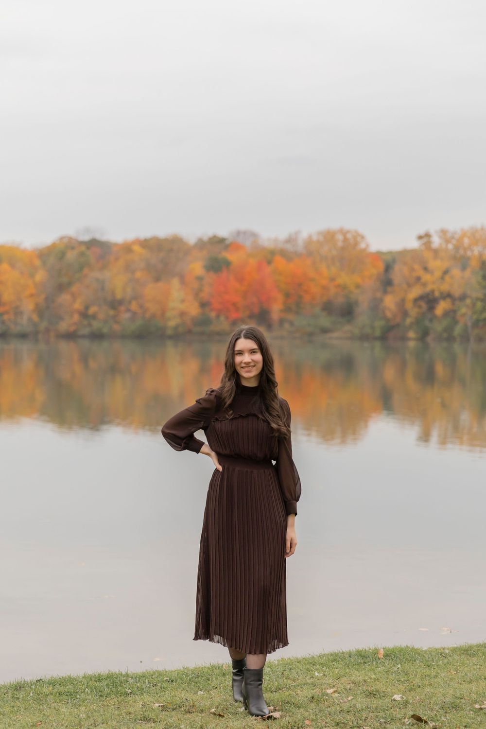 teenage girl in a brown dress standing in front of a lake in troy michigan in october