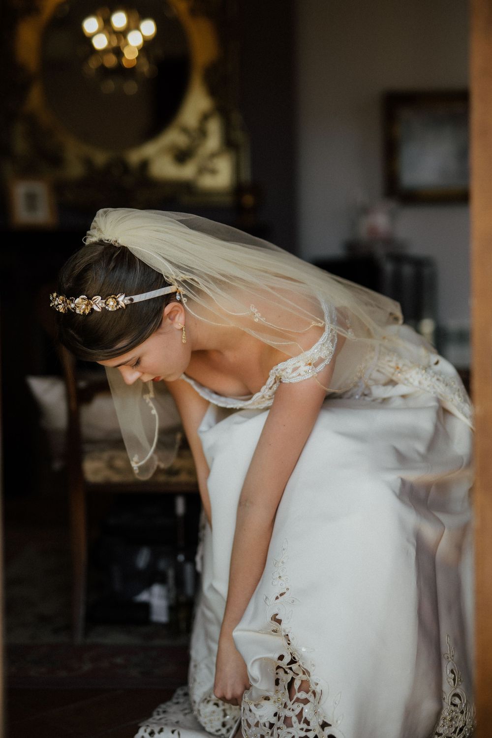 Wedding dress and veil detail as bride bends down in elegant room setting. Destination Wedding in Malaga, Spain.