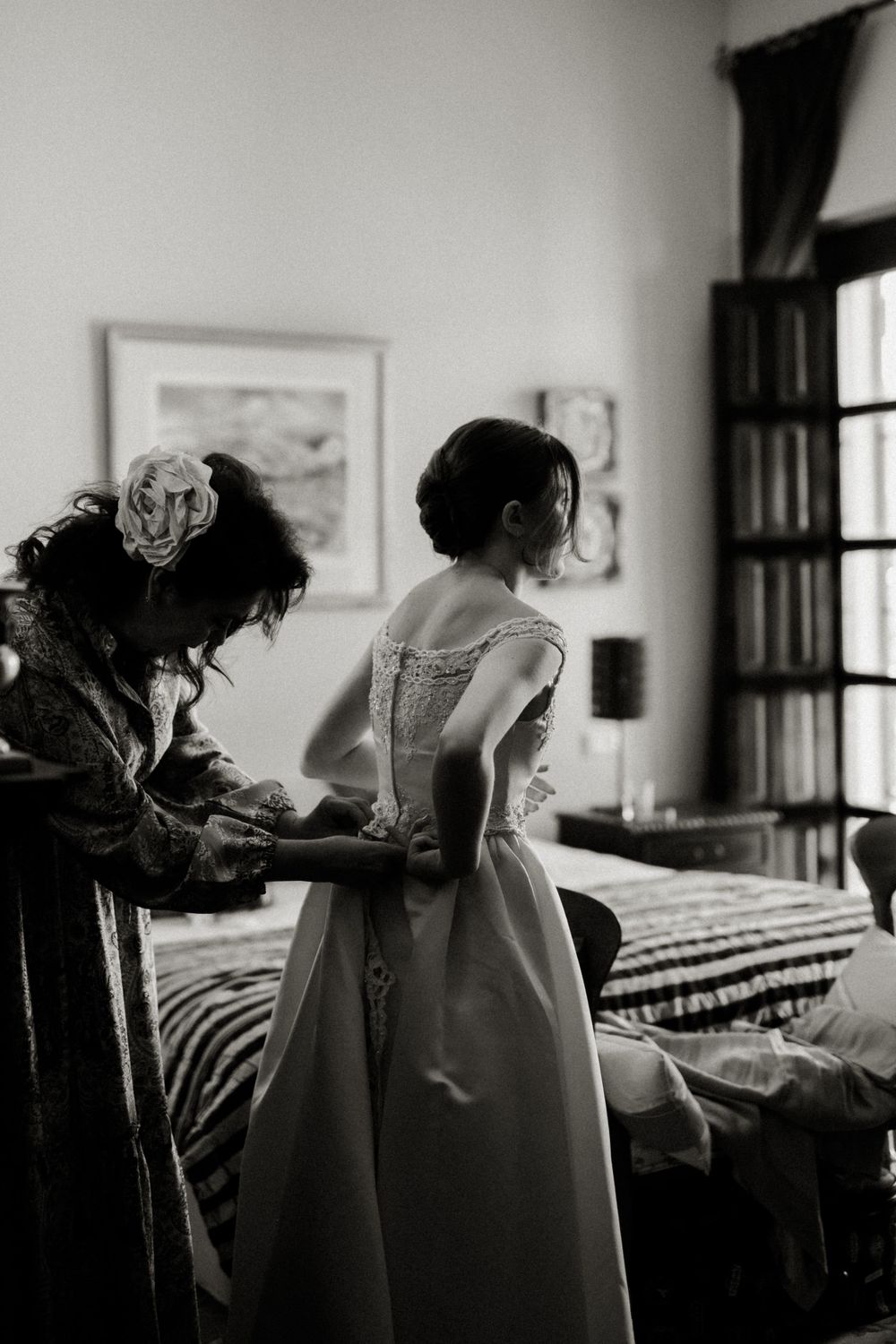 Black and white image of wedding dress preparation in a bedroom. Destination Wedding in Malaga, Spain.